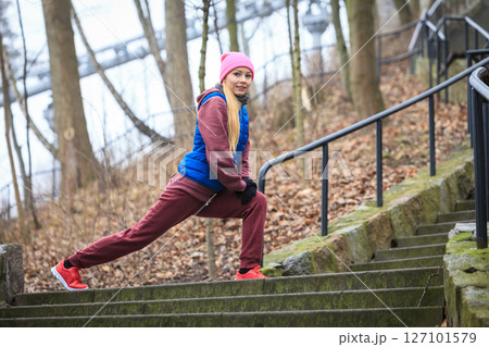 Woman wearing sportswear exercising outside during autumn 127101579