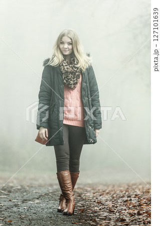Woman walking in park in foggy day Woman walking in park in foggy day 127101639