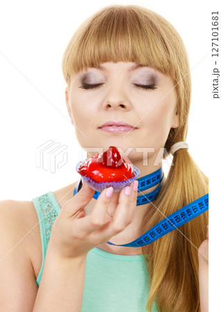 Woman holds cupcake trying to resist temptation Woman holds cupcake trying to resist temptation 127101681