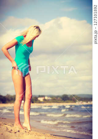 Woman walking on beach wearing swimsuit 127101892