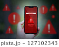 hand holding smartphone with red caution danger app icons 127102343