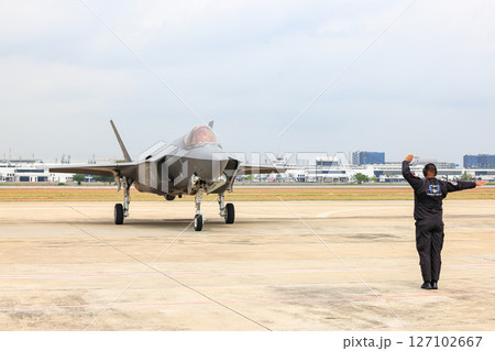 Airbase marshalling supervisor at the airbase apron on duty to take F35 taxiing to the parking place. Airbase marshalling supervisor at the airbase apron on duty to take F35 taxiing to the parking place. 127102667