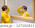 Portrait of an elderly woman in front of a mirror. A beautiful red-haired senior carefully examines her reflection in the mirror. 127102813