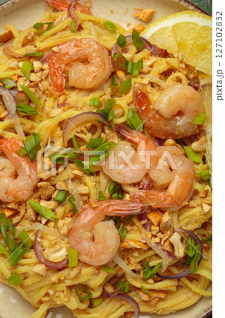 Pad thai noodles with shrimps, peanuts, green onions and lemon slice close up 127102832