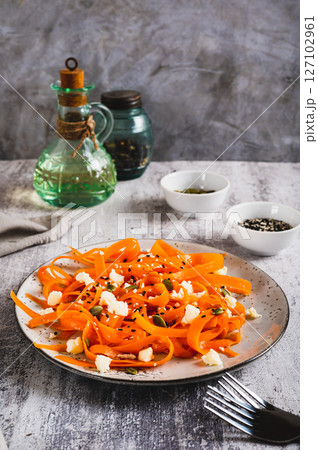 Spicy carrot, ricotta and pumpkin seed salad on a plate on a table vertical view Spicy carrot, ricotta and pumpkin seed salad on a plate on a table vertical view 127102961