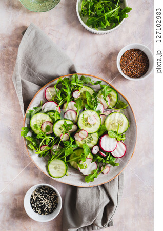 Cucumber, radish and greens salad mix on a plate on the table top and vertical view Cucumber, radish and greens salad mix on a plate on the table top and vertical view 127102983