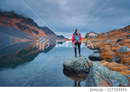 Young woman standing on a rock on alpine mountain lake. 127103453