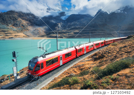 Red train is moving along railway in swiss alps mountain. Autumn Red train is moving along railway in swiss alps mountain. Autumn 127103492