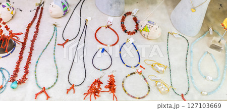 Handmade beaded jewelry and coral accessories displayed on white surface. Artisan craftsmanship, colorful fashion, and coastal souvenir design. 127103669