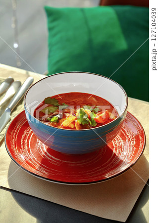 Tom yum soup served in blue bowl on red plate with cutlery aside Tom yum soup served in blue bowl on red plate with cutlery aside 127104039