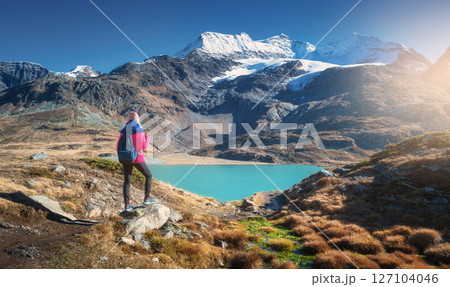 Young woman on trail, snowy mountains, lake and glaciar at sunse 127104046