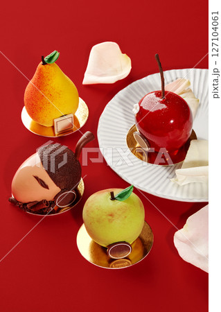 Delicious fruit shaped cakes resembling apple, pear, cherry and acorn on red background 127104061