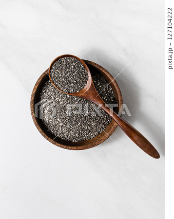Top view of chia seeds in a wooden bowl with a spoon. Healthy superfood concept Top view of chia seeds in a wooden bowl with a spoon. Healthy superfood concept 127104222