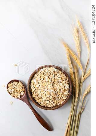 Top view of a wooden bowl with rolled oats and a wooden spoon Top view of a wooden bowl with rolled oats and a wooden spoon 127104224