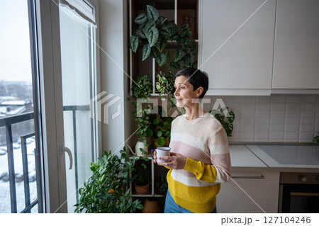 Female relaxing, spending personal time enjoying solitude while looking at winter view outside. Female relaxing, spending personal time enjoying solitude while looking at winter view outside. 127104246