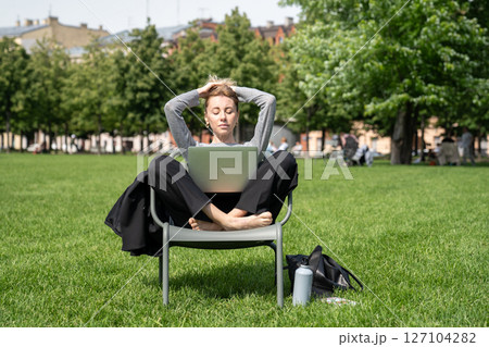 Relaxed woman rest with eyes closed while listen to lectures on laptop in park. Online school, study Relaxed woman rest with eyes closed while listen to lectures on laptop in park. Online school, study 127104282