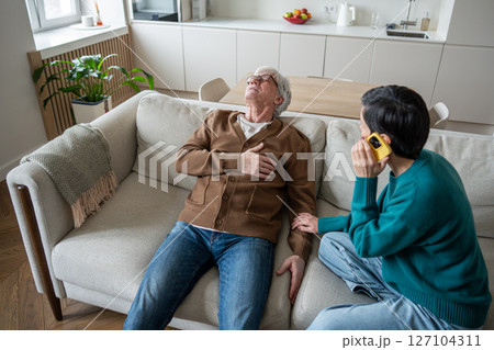 Elderly man collapses unconscious on sofa with breathing difficulties, wife calls emergency services 127104311
