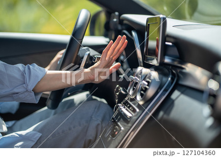 Female hand checks flow of cold air from air conditioner inside car, suffer from heat in vehicle 127104360