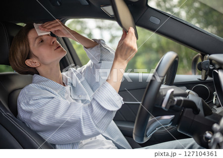 Woman drives car with broken air conditioning in hot summer weather wipes sweat paper napkin. Woman drives car with broken air conditioning in hot summer weather wipes sweat paper napkin. 127104361