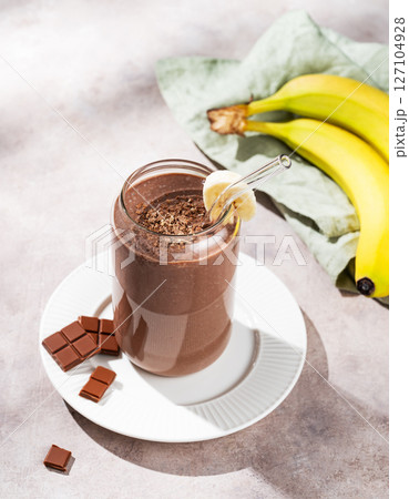 Vegetarian chocolate smoothie with banana in a glass on a light  background with fresh fruits 127104928