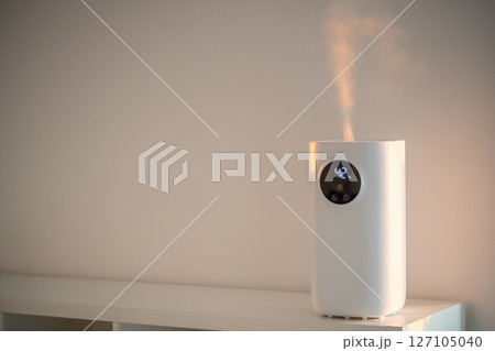 Modern humidifier at home, moistens dry air in living room. Apartment with moisturizer. Modern humidifier at home, moistens dry air in living room. Apartment with moisturizer. 127105040