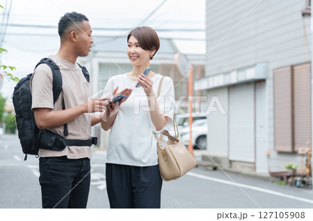 スマホ翻訳アプリで外国人に道案内する女性 127105908