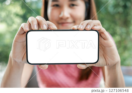 Close-up of a woman holding a smartphone with a blank screen, perfect for mockups and design presentations. 127106548