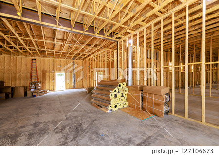 Construction underway with wooden framing, insulation, materials stacked inside new building. 127106673