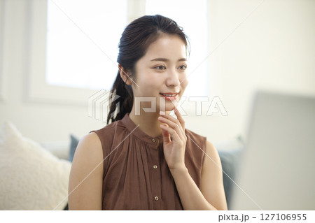 リビングでノートパソコンに向かう20代女性 リビングでノートパソコンに向かう20代女性 127106955