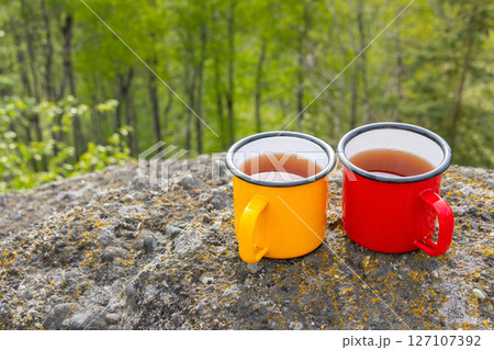Colorful camping Cups on Rocks Overlooking Valley Colorful camping Cups on Rocks Overlooking Valley 127107392