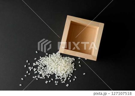 黒背景に空の升とこぼれたコメ 127107518