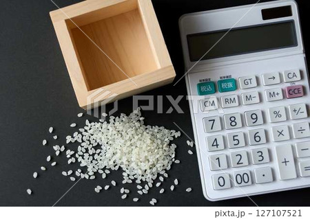 升からこぼれた少しのコメと電卓 127107521