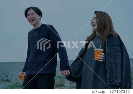 曇りの日の夕方の砂丘を歩く若い男女 曇りの日の夕方の砂丘を歩く若い男女 127107839