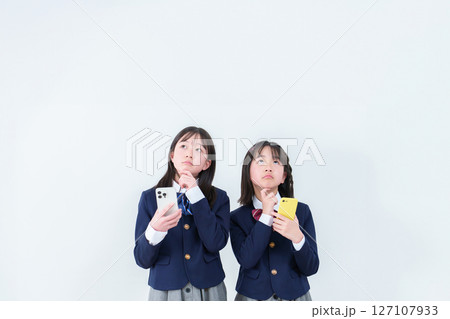 スマートフォンを持ちながら考え事をする女子学生 127107933