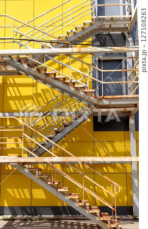 unique metal staircase with vibrant yellow background showcasing shadows in industrial setting. unique metal staircase with vibrant yellow background showcasing shadows in industrial setting. 127108263