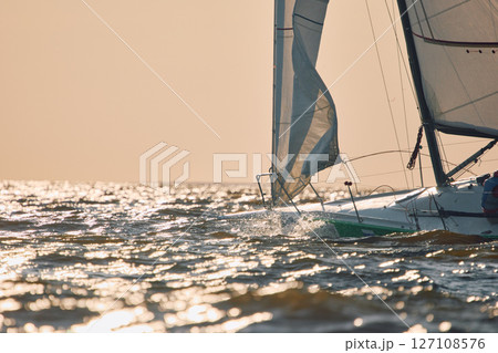 Sailing regatta in the Gulf of Finland at sunset, sailing yacht competing in a race, splashing water from under the boat, teamwork, board the boat 127108576