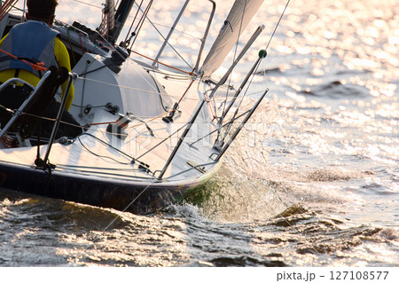 Sailing regatta in the Gulf of Finland at sunset, sailing yacht competing in a race, splashing water from under the boat, teamwork, board the boat 127108577