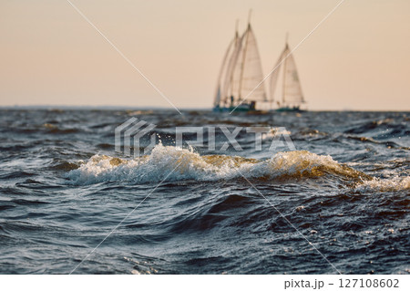 Sailing regatta in the Gulf of Finland at sunset, two sailing yachts competing in a race, splashing water from under the boats, teamwork, board the boat 127108602