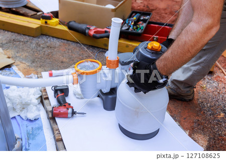 Assembling components of pool filtration system on works day in backyard setting, near swimming pool 127108625