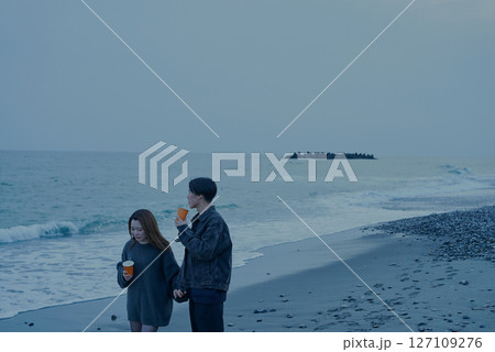 夕暮れの海岸を歩く若い男女 夕暮れの海岸を歩く若い男女 127109276