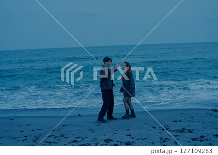 夕暮れの海岸を歩く若い男女 夕暮れの海岸を歩く若い男女 127109283