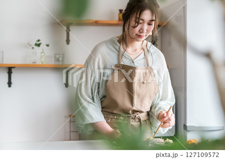 キッチンで料理する若いアジア人女性 キッチンで料理する若いアジア人女性 127109572