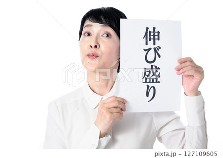 伸び盛りと書かれた紙を持つ中年女性 127109605