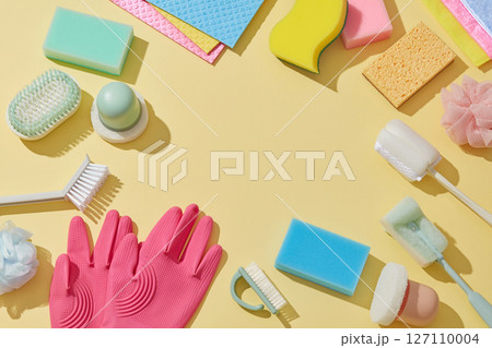 Flat lay of a vibrant cleaning set including gloves, brushes, cloths, and soap sits on a pastel surface, ready for use in household or janitorial cleaning tasks. Flat lay of a vibrant cleaning set including gloves, brushes, cloths, and soap sits on a pastel surface, ready for use in household or janitorial cleaning tasks. 127110004
