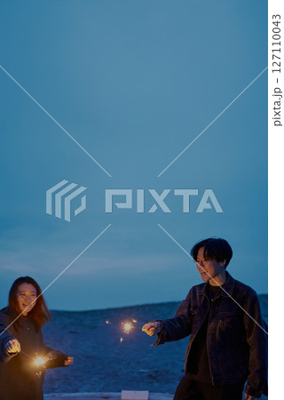 夜の海岸で手持ち花火をする若い男女 夜の海岸で手持ち花火をする若い男女 127110043