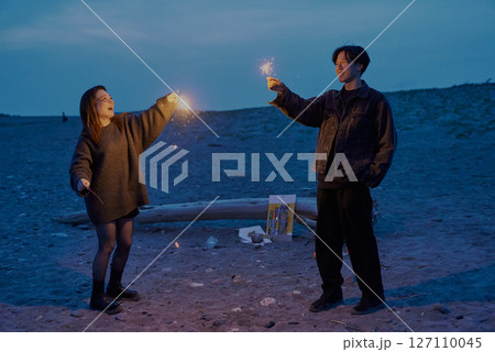 夜の海岸で手持ち花火をする若い男女 夜の海岸で手持ち花火をする若い男女 127110045
