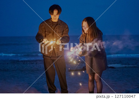 夜の海岸で手持ち花火をする若い男女 夜の海岸で手持ち花火をする若い男女 127110047