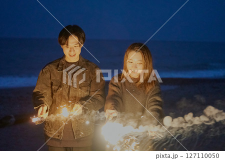 夜の海岸で手持ち花火をする若い男女 夜の海岸で手持ち花火をする若い男女 127110050