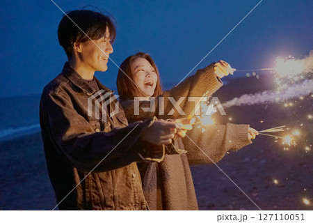 夜の海岸で手持ち花火をする若い男女 夜の海岸で手持ち花火をする若い男女 127110051