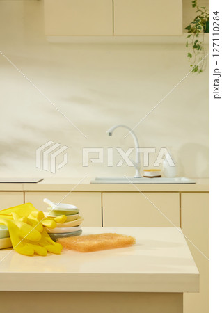 Yellow rubber gloves and cleaning supplies near the sink in a cozy beige kitchen, lifestyle in everyday household activities. Empty space for add text and display product Yellow rubber gloves and cleaning supplies near the sink in a cozy beige kitchen, lifestyle in everyday household activities. Empty space for add text and display product 127110284